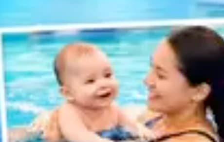 A mother holding her smiling baby in the pool during a Baby & Me class
