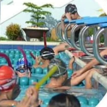 A group of children in goggles lined up at the pool edge during a lesson