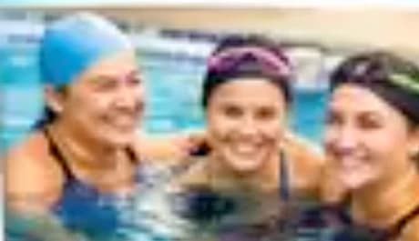 Three adult women smiling together in the pool during a ladies' group class